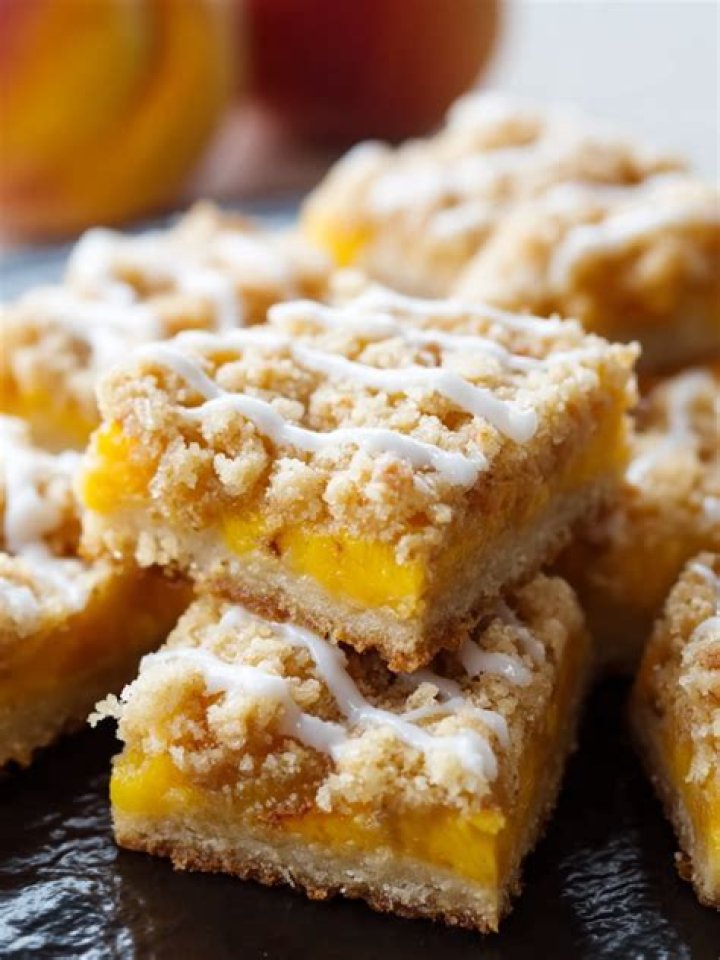 Two peach crumb bars topped with vanilla ice cream.